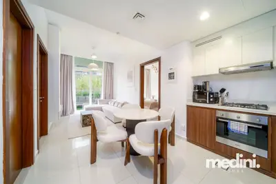 Open-plan kitchen and dining area with a round table, chairs, oven, and appliances