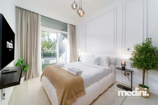 Primary bedroom with a double bed, tan throw, pendant lights, and panel moulding