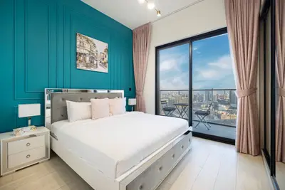 Master bedroom with teal accent wall, silver framed bed and balcony access
