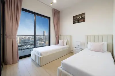 Twin bedroom with pink curtains and skyline views through the tall window