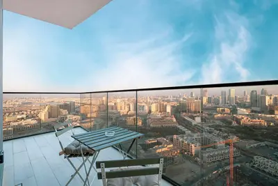 Balcony bistro table and chairs above a sweeping view of the JVC skyline