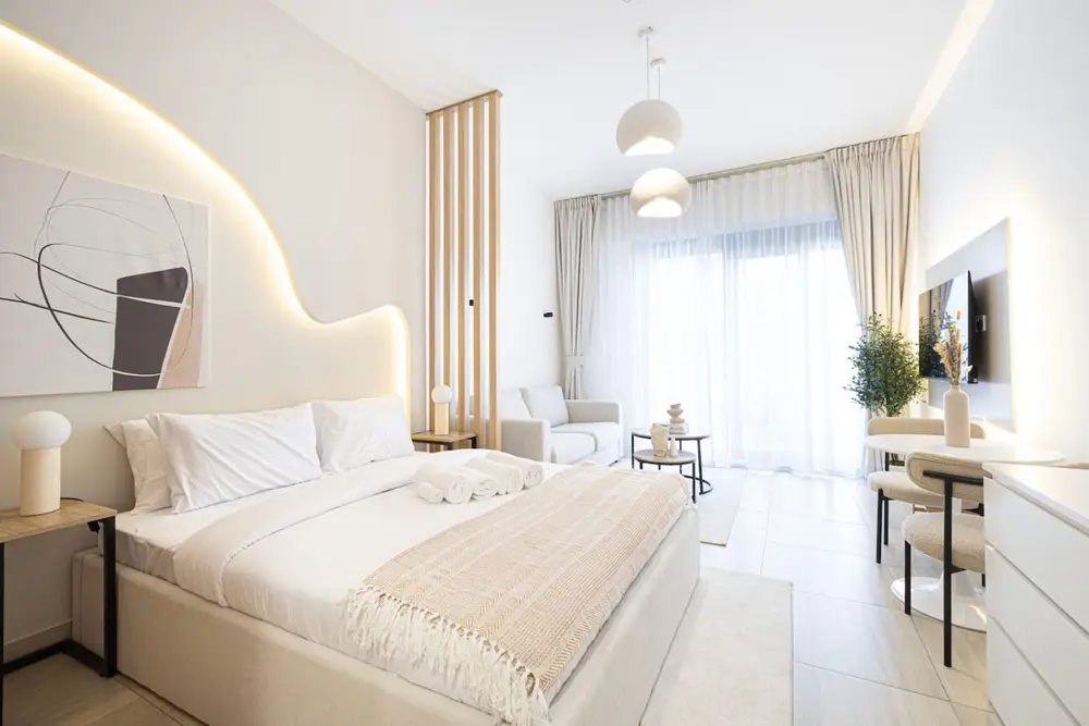 Bedroom with arched backlit headboard, double bed, sofa and desk corner