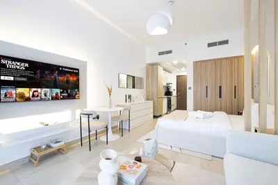 Studio overview showing TV wall, dining table, kitchen corridor and wardrobe