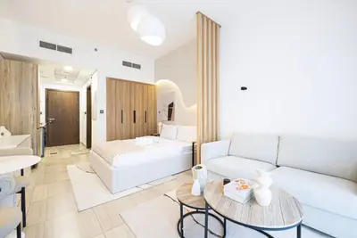 Studio from entrance side with sofa, nesting coffee tables and bed beyond
