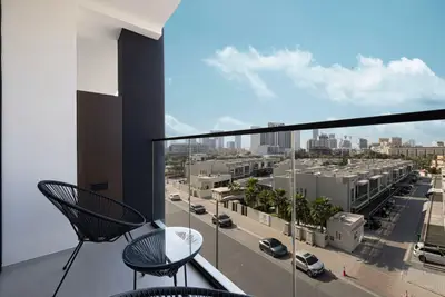 Balcony with two chairs and side table overlooking a residential street and skyline