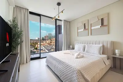 Bedroom with king bed, balcony window, city view and pendant track lighting