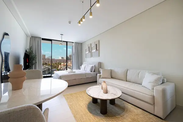 Open-plan studio with sofa, marble coffee table, bed and large city-view window