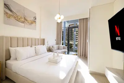 Bedroom with double bed, white linens, and TV on a marble-effect wall panel