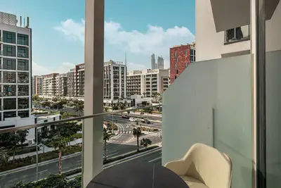 Balcony with small round table and chair overlooking a tree-lined street