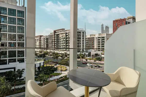 Balcony with two cream chairs and round table, cityscape with tall tower in the distance