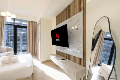 TV wall with marble-look panel and wooden slats, floor mirror beside tall windows