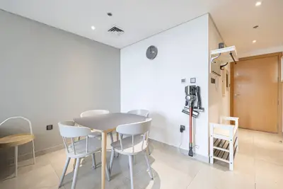 Dining area with a round table and four white chairs near the entry door
