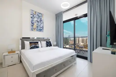 Bright bedroom with double bed and balcony doors framing city views