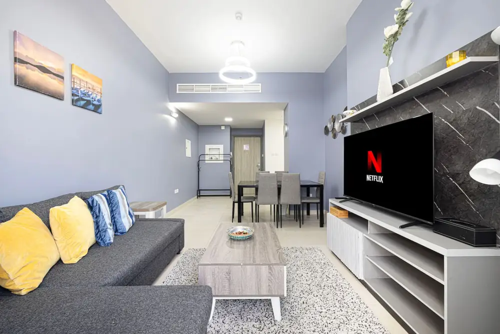 Open living room with grey corner sofa, wall-mounted TV and dining nook behind