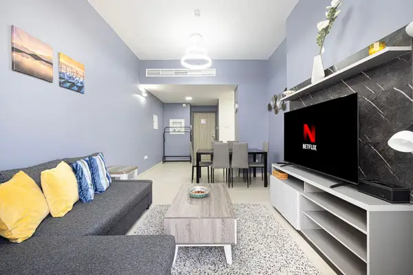 Open living room with grey corner sofa, wall-mounted TV and dining nook behind