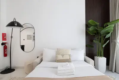 Bedroom from a low angle showing folded towels, round mirror and potted plant