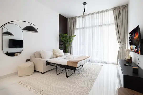 Living room with beige sofa, round arch mirror and large draped window
