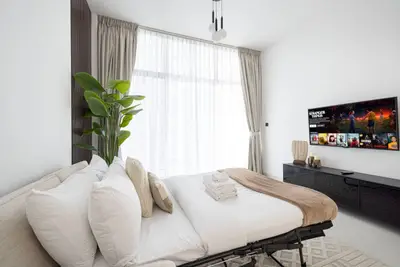 Bedroom with double bed, wall-mounted TV and floor-to-ceiling curtained window