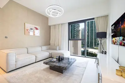 Bright living room with beige corner sofa, marble coffee table and city view
