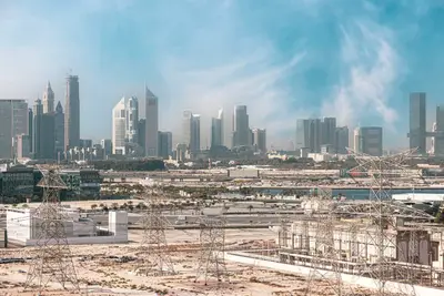 Panoramic city skyline view with skyscrapers and construction sites under a hazy blue sky
