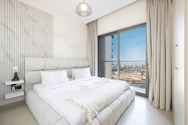 Bedroom with upholstered headboard and floor-to-ceiling window, city skyline beyond