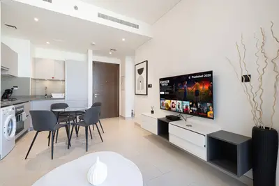 Living and dining area with wall-mounted TV, round table and four grey chairs