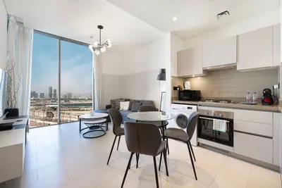 Open-plan kitchen and dining area with four chairs and a city view through large windows