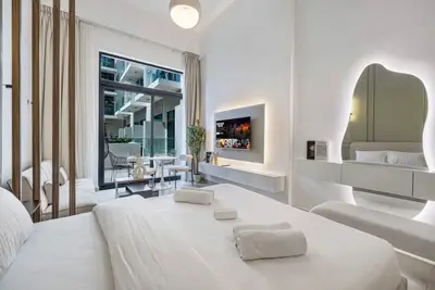 The bed faces a floating TV unit, with the sunny terrace just beyond the glass