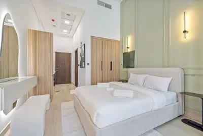 Queen bed and TV seen from the vanity corner, with the entry hall behind