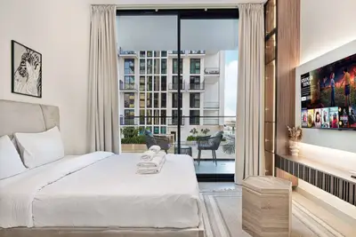 Bed with white linen, two wall prints and a floor-to-ceiling glass door to the balcony