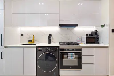 Full kitchen run with white cabinetry, gas hob, oven and a front-loading washing machine