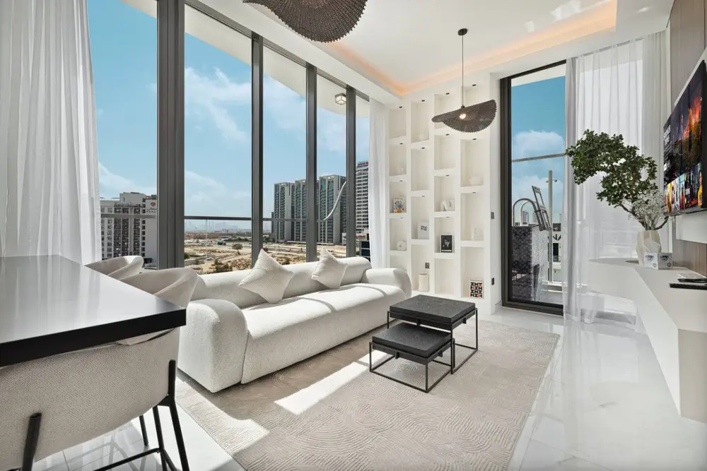 Bright living room with white sofa, floor-to-ceiling windows, and city view