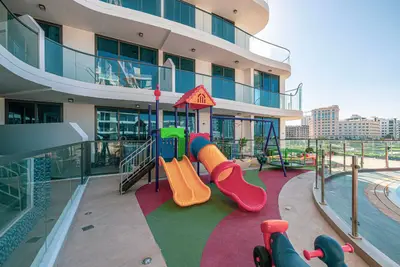 Outdoor children's playground with slide, swings, and colourful flooring