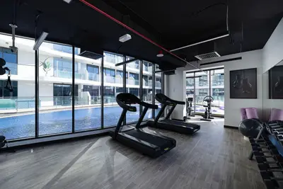 Gym with three treadmills facing glazed windows overlooking the pool