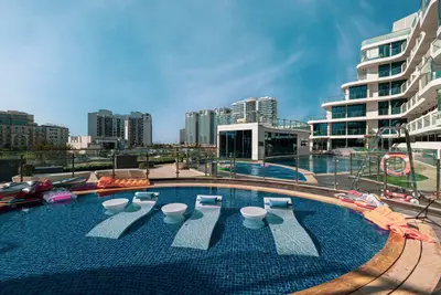 Circular pool with in-water sun loungers and towers in the background