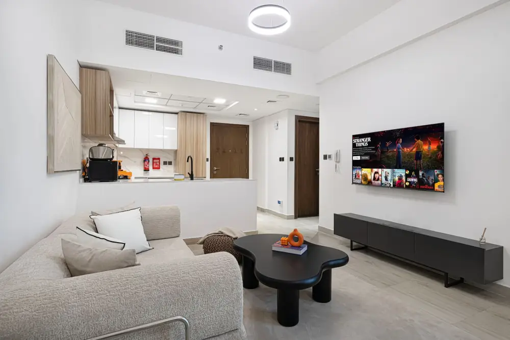 Living room with grey sofa, round coffee table, and wall-mounted TV