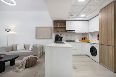 Open kitchen with island counter, washing machine, and sofa behind