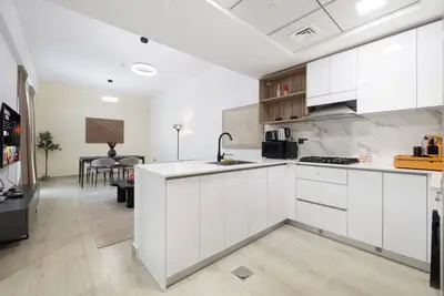 Kitchen with white gloss island, black sink tap, and dining table beyond