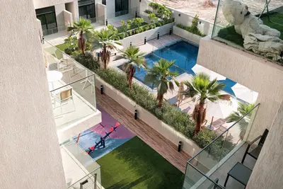 Aerial view of courtyard pool, palm trees, and fitness area below