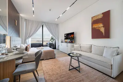 Living area with white sofa, wall-mounted TV, dining set and sheer curtained window