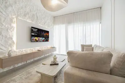 Living room with beige sectional sofa, TV on a stone accent wall and wooden TV unit