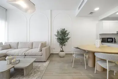 Open living and dining room with large sofa, round table and arch wall mouldings