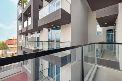 Balcony with glass railing overlooking the building facade and corridors