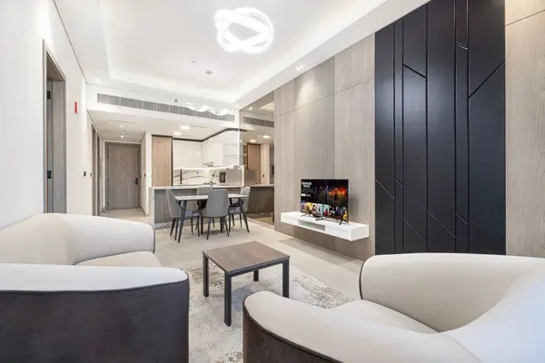 Living room with two sofas, wall-mounted TV, and kitchen visible beyond