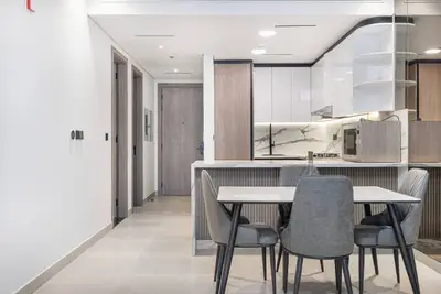 Dining table with four grey chairs facing the open kitchen and entrance hallway