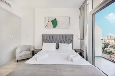 Gray quilted headboard, armchair, wall artwork, and open balcony door