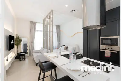 Open-plan layout showing the kitchen peninsula, bar stools, sofa, and partition