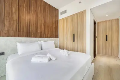 Bedroom showing built-in wardrobe, wood panel headboard wall, and white bedding