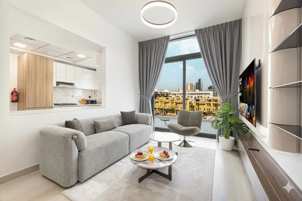 Living room with grey sofa, wall-mounted TV, and city-view window