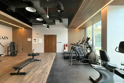 Building gym with cardio machines, bench press, and slatted wood ceiling